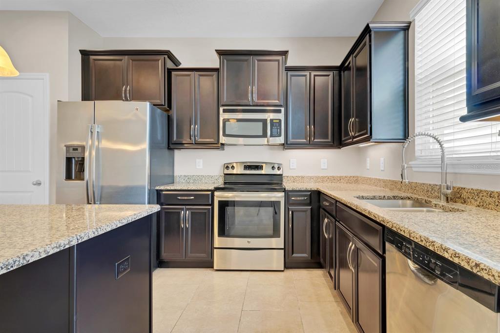 1578 Softshell Street St. Cloud, FL 34771 - Photo 7 of 27 a kitchen with stainless steel appliances granite countertop a sink stove and refrigerator
