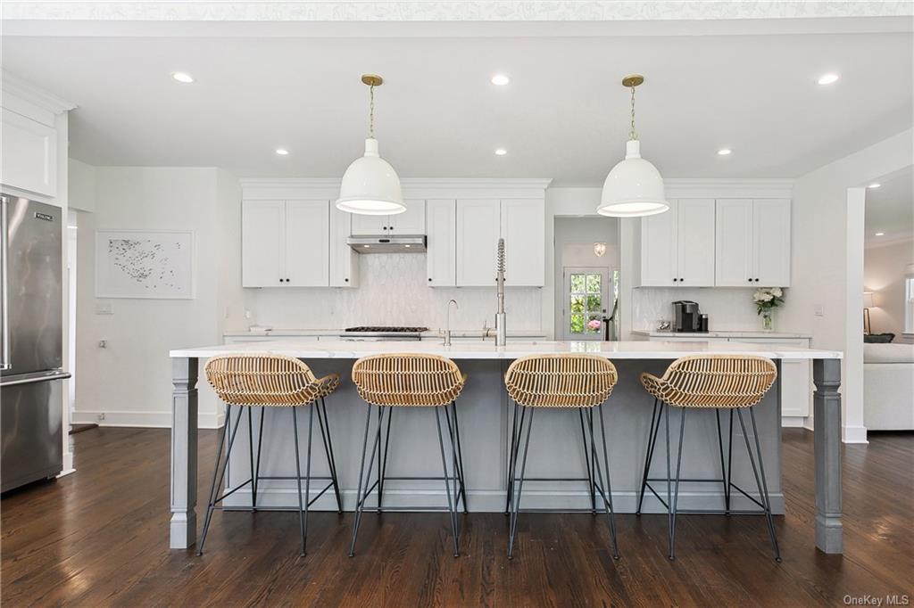 a kitchen with stainless steel appliances granite countertop a dining table chairs stove and white cabinets