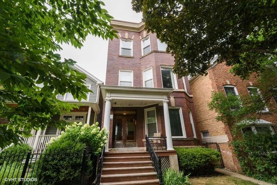 front view of a house with potted plants and a tree