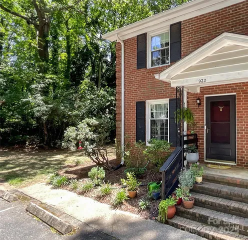 a view of a house with potted plants and a table and chairs