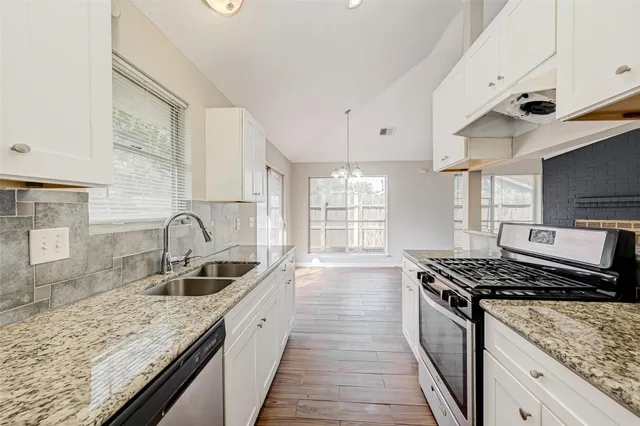 a kitchen with stainless steel appliances granite countertop a sink stove and cabinets