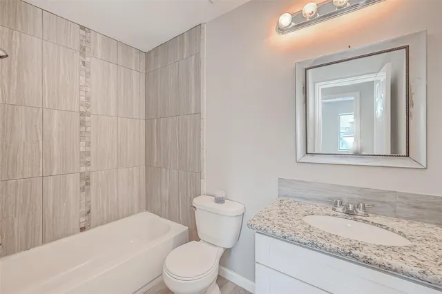 a bathroom with a granite countertop sink a toilet and a mirror