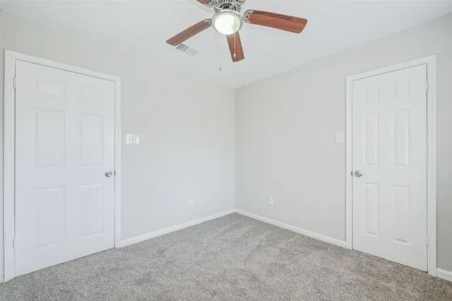 an empty room with closet and a chandelier fan