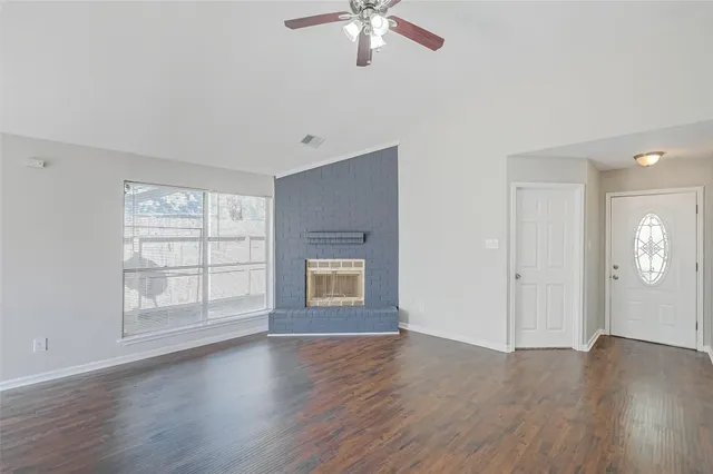an empty room with wooden floor chandelier and windows
