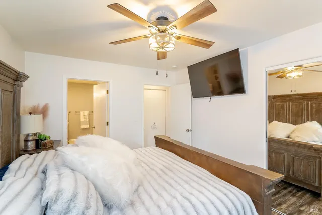 a bedroom with a large bed a flat tv screen and a chandelier