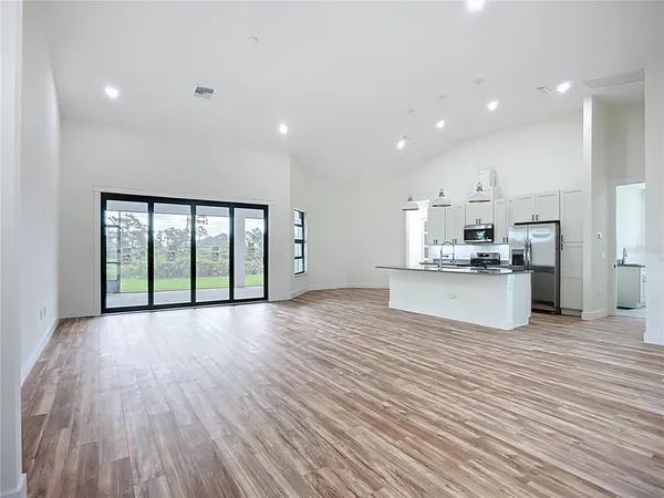 a view of kitchen with granite countertop a stove top oven a sink and white cabinets with wooden floor