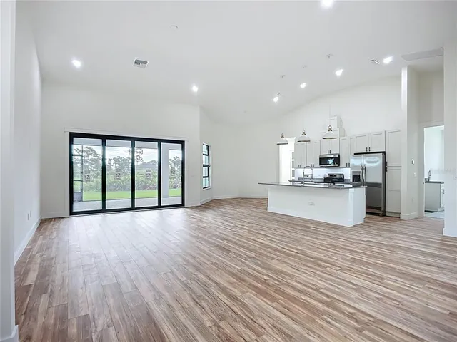 a view of kitchen with granite countertop a stove top oven a sink and white cabinets with wooden floor