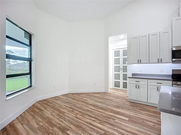 a kitchen with stainless steel appliances granite countertop a stove a sink dishwasher and white cabinets with wooden floor