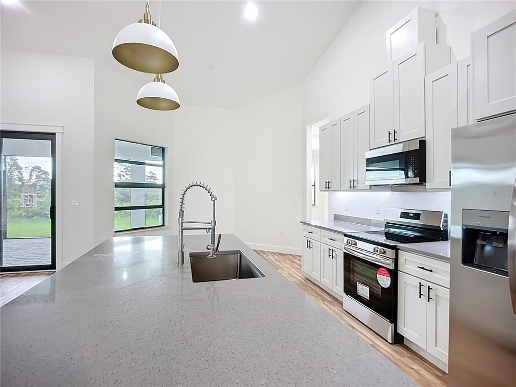 15 Heave Lane Placida, FL 33946 - Photo 27 of 70 a kitchen with stainless steel appliances granite countertop a stove a sink dishwasher and white cabinets with wooden floor