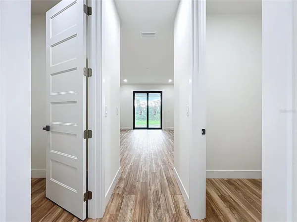 an empty room with wooden floor closet and windows