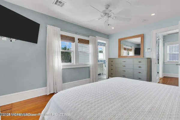a bedroom with a large bed and a flat tv screen on dresser