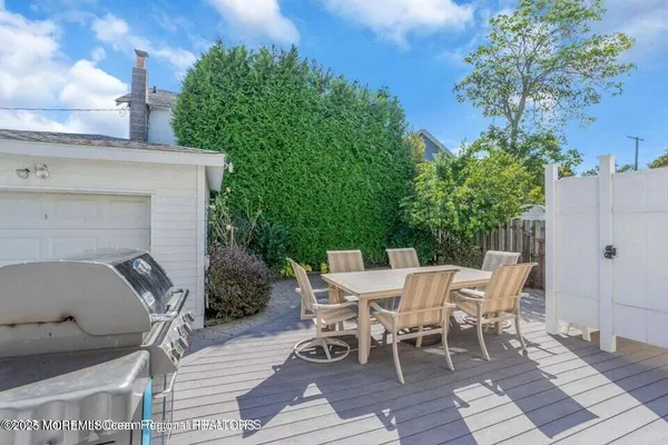 a view of a patio with table and chairs with wooden floor and fence