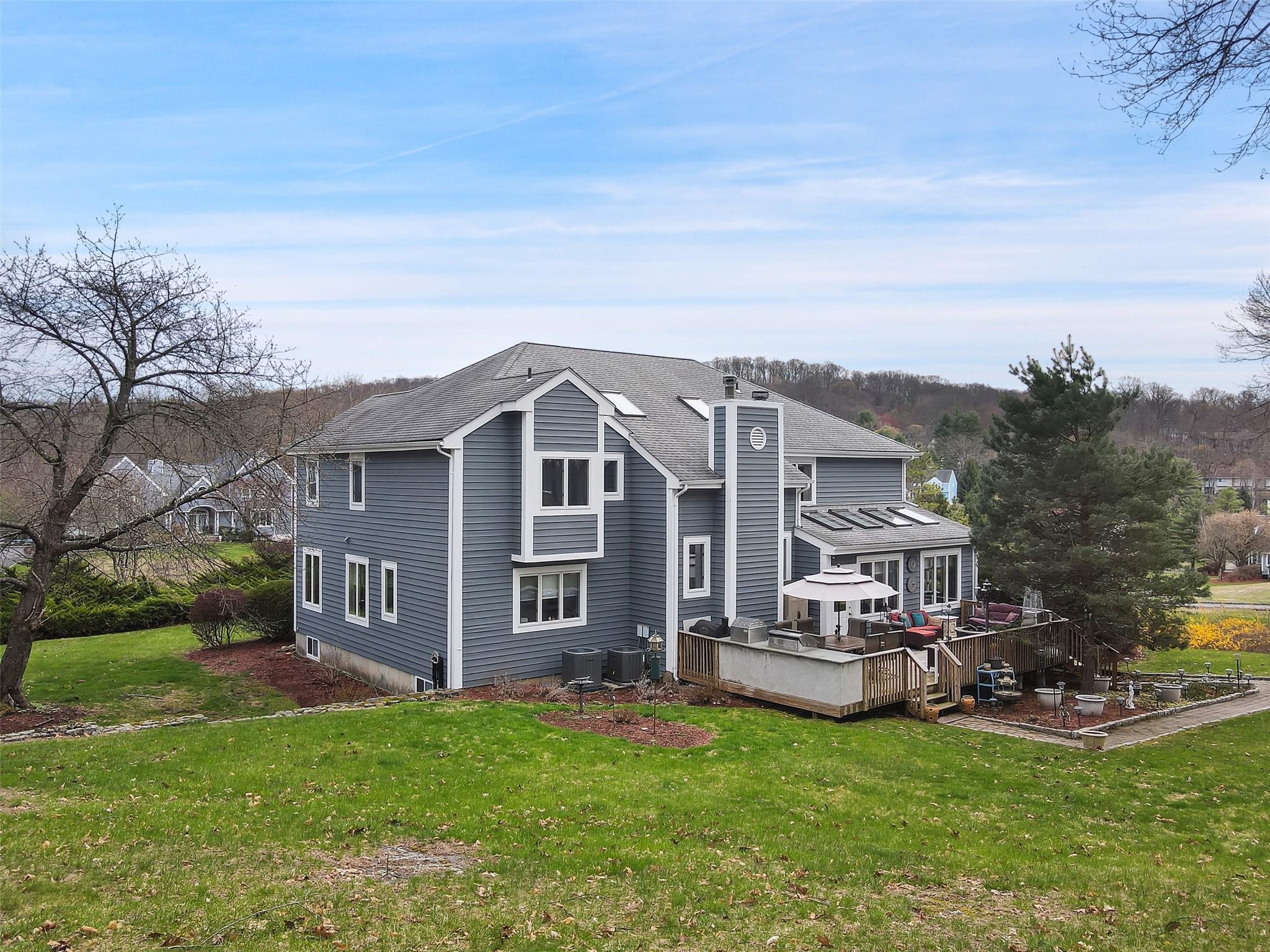 13 Cross Road Cortlandt Manor, NY 10567 - Photo 1 of 1 Back of house with a yard, a wooden deck, central AC unit, and roof with shingles