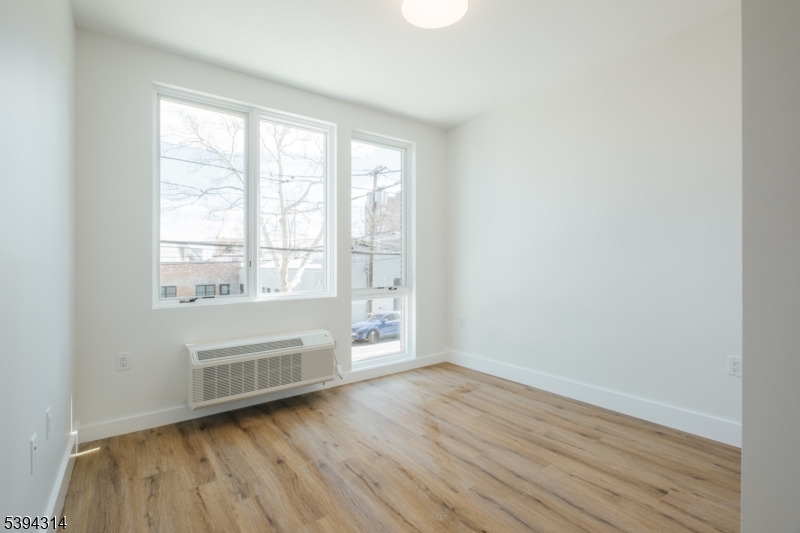67 Summer Avenue, Unit 101 Newark, NJ 07104 - Photo 11 of 26 an empty room with wooden floor and windows