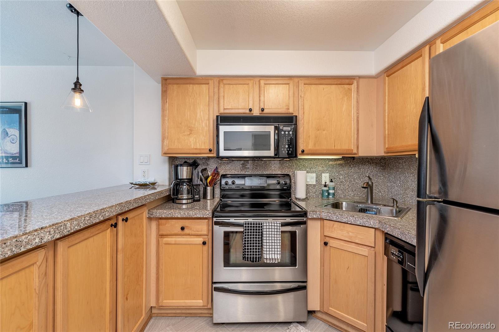 1833 North Williams Street, Unit 504 Denver, CO 80218 - Photo 6 of 19 a kitchen with stainless steel appliances granite countertop a stove a sink and a microwave