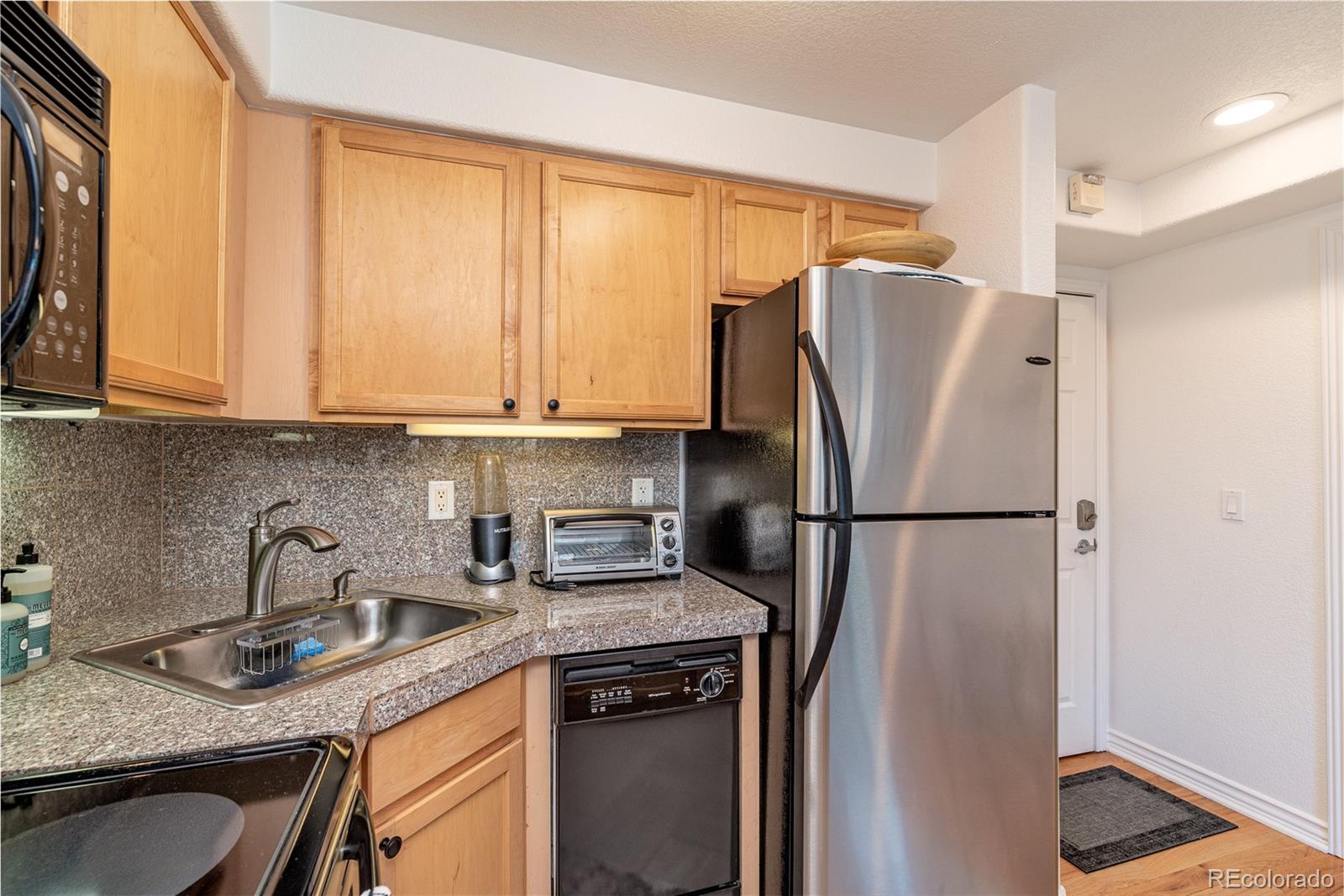 1833 North Williams Street, Unit 504 Denver, CO 80218 - Photo 8 of 19 a kitchen with stainless steel appliances granite countertop a refrigerator and a sink