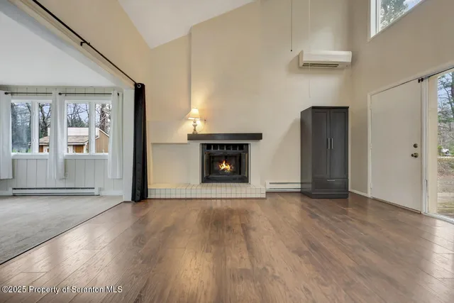 an empty room with wooden floor fireplace and windows