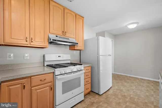 a kitchen with stainless steel appliances granite countertop white cabinets and a refrigerator a stove top oven with wooden floor