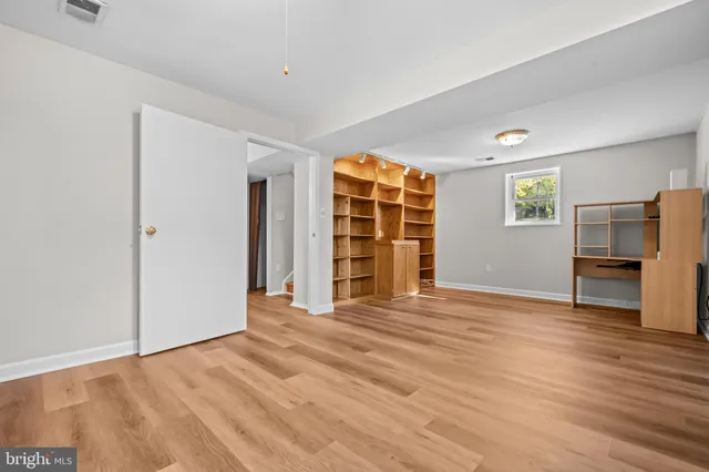 a view of an empty room with a window and a kitchen
