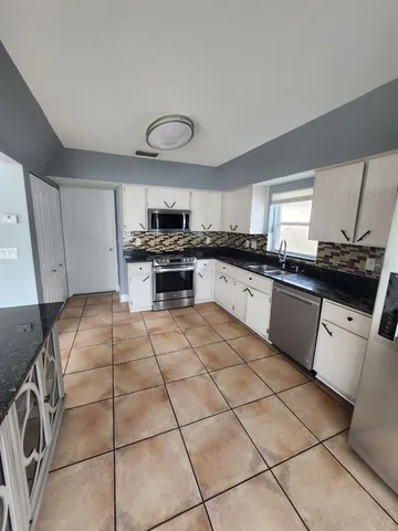 a large kitchen with granite countertop a stove a sink dishwasher and a refrigerator