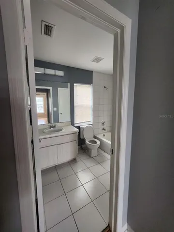 a bathroom with a granite countertop sink a toilet a mirror and bathtub