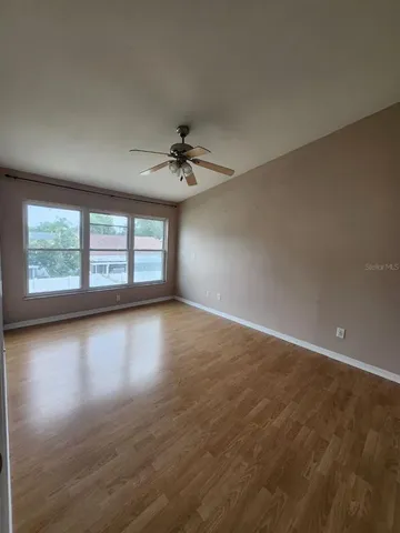 a view of empty room with wooden floor and fan