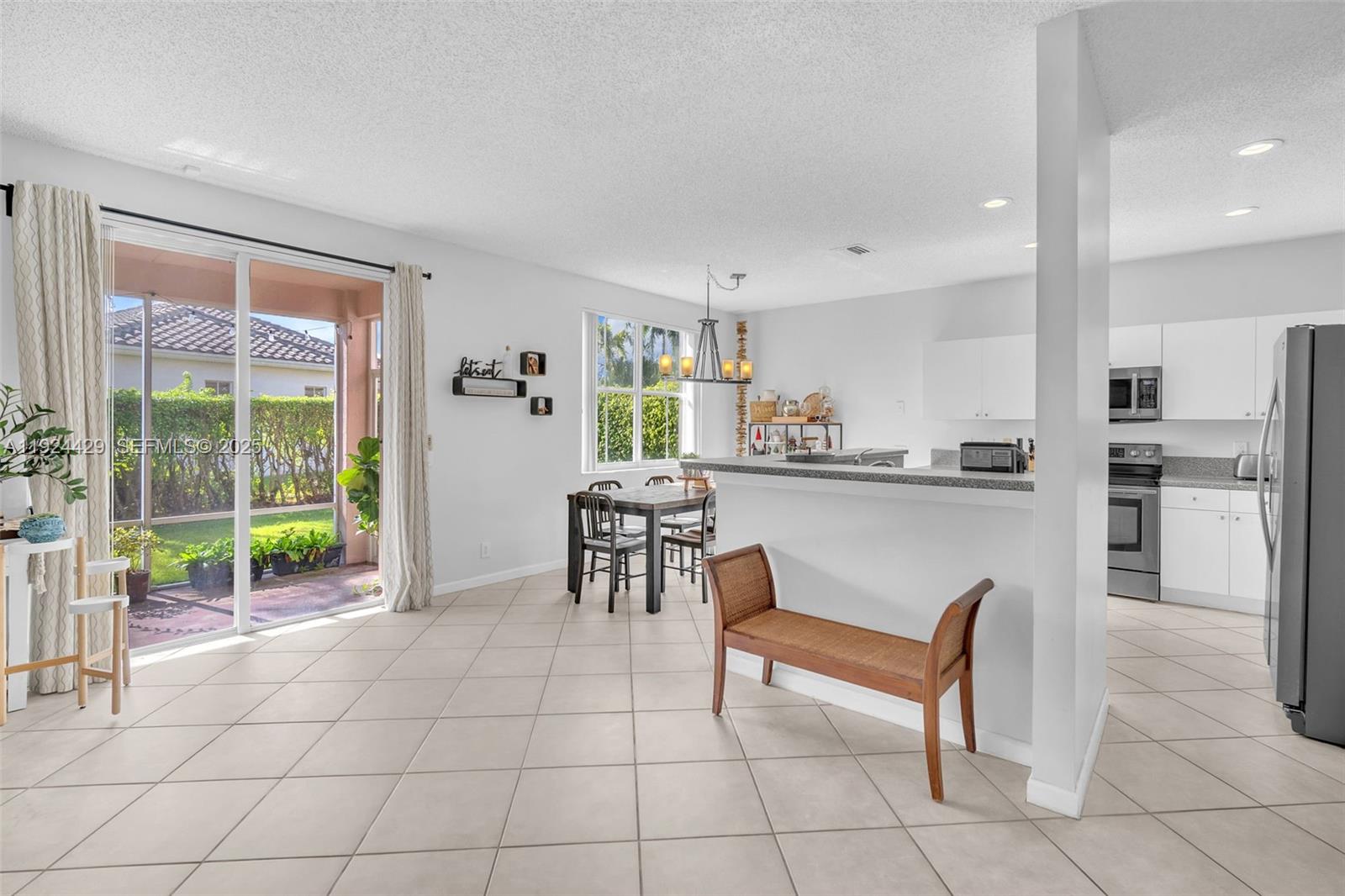 1058 Tupelo Way Weston, FL 33327 - Photo 12 of 43 a living room with furniture a floor to ceiling window and kitchen view