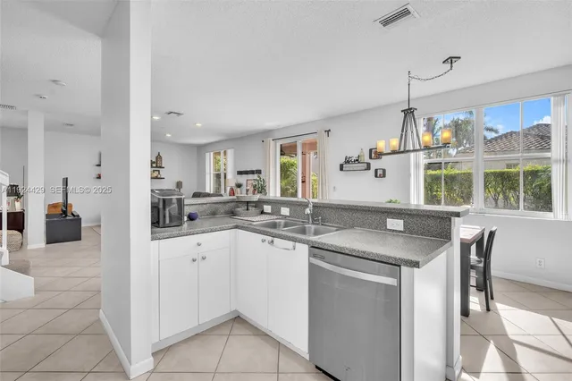 a kitchen with stainless steel appliances granite countertop a refrigerator sink and white cabinets