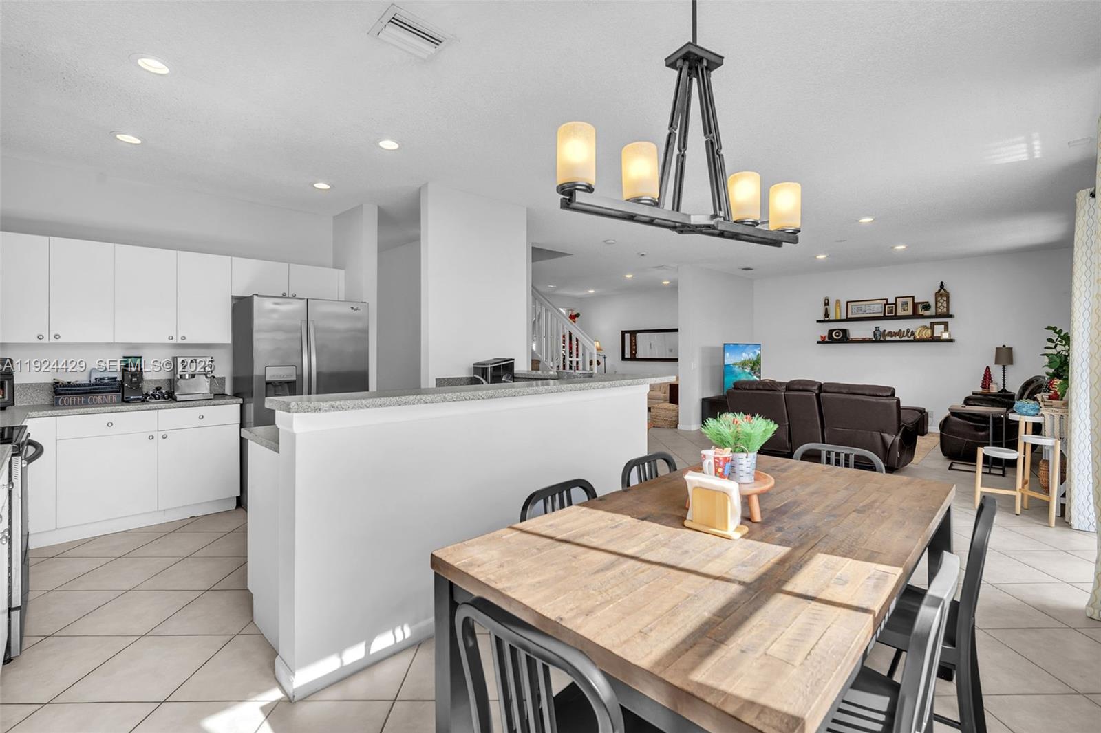 1058 Tupelo Way Weston, FL 33327 - Photo 16 of 43 a kitchen with stainless steel appliances kitchen island granite countertop a dining table chairs and white cabinets