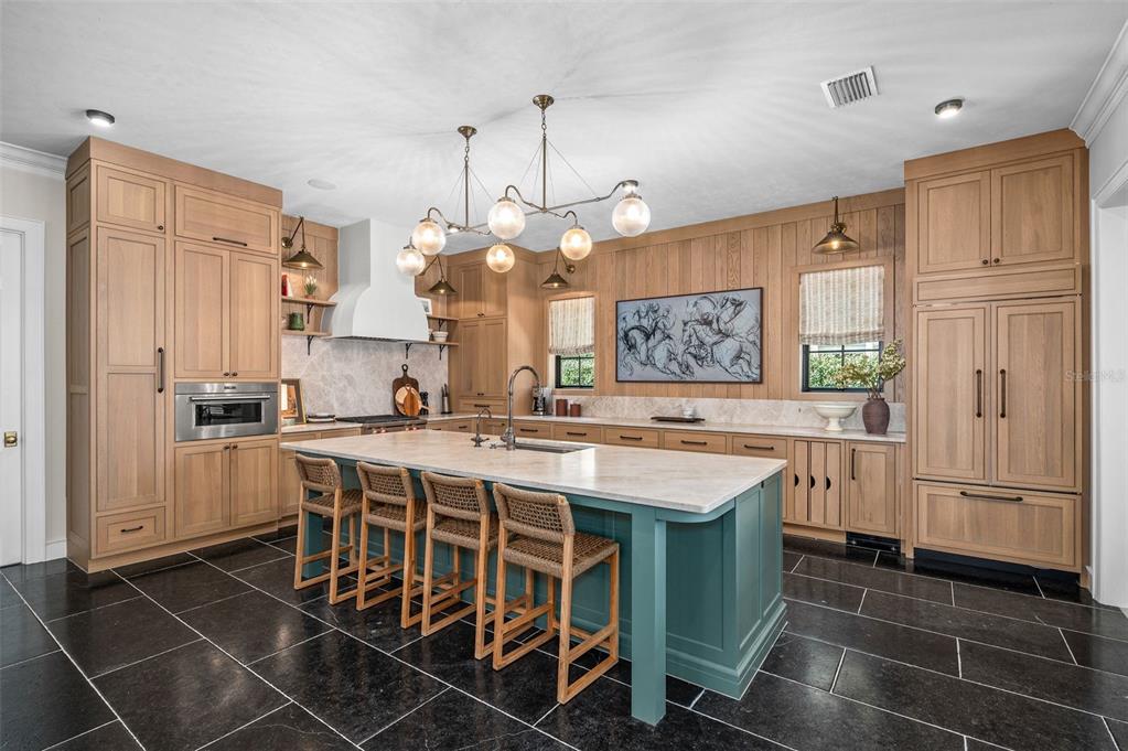 623 Southwest 93rd Street Gainesville, FL 32607 - Photo 70 of 100 a kitchen with kitchen island granite countertop a table chairs and a refrigerator