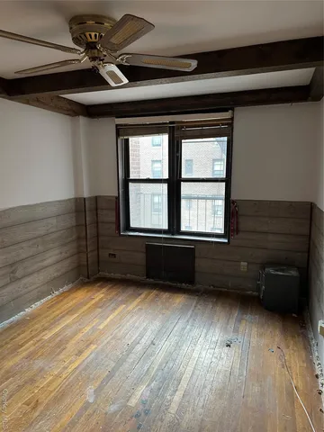 a view of an empty room with a window and wooden floor