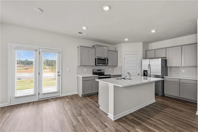 a kitchen with stainless steel appliances a refrigerator a sink a stove a microwave and cabinets