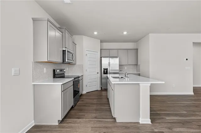 a kitchen with granite countertop a stove top oven a sink dishwasher and white cabinets with wooden floor