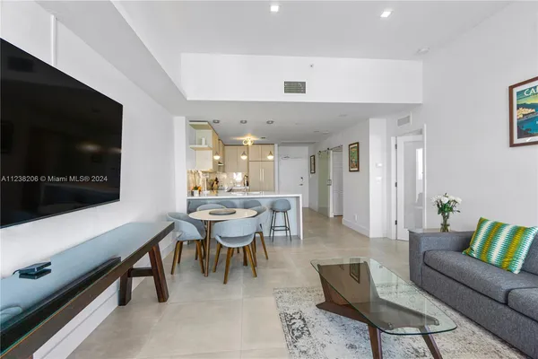 a living room with furniture a flat screen tv and kitchen view