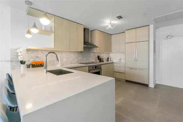 a kitchen that has a lot of white cabinets and stainless steel appliances