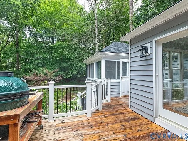 a balcony with wooden floor and fence next to a yard