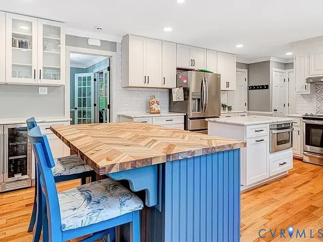 a kitchen with kitchen island granite countertop wooden cabinets a stove a sink dishwasher and a refrigerator with wooden floor