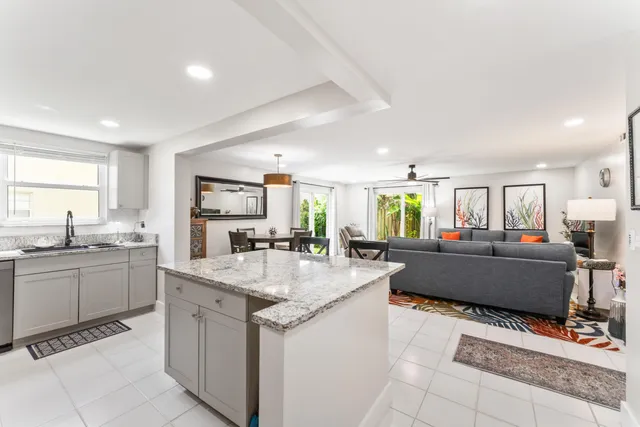 a large kitchen with kitchen island a sink a counter top space and living room view