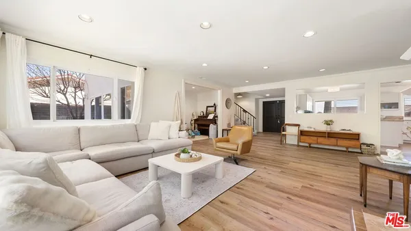 a living room with furniture kitchen view and a large window