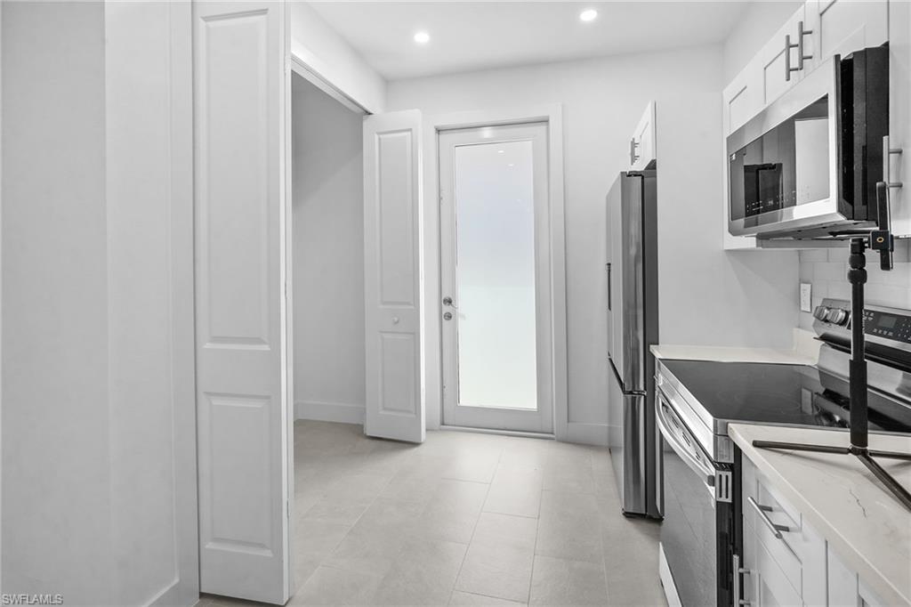 2936 40th Avenue Southeast Naples, FL 34117 - Photo 11 of 49 Kitchen with stainless steel appliances, white cabinets, recessed lighting, and light stone countertops