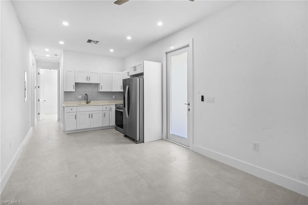 2936 40th Avenue Southeast Naples, FL 34117 - Photo 30 of 49 Kitchen featuring light countertops, white cabinets, decorative backsplash, stainless steel appliances, and a ceiling fan