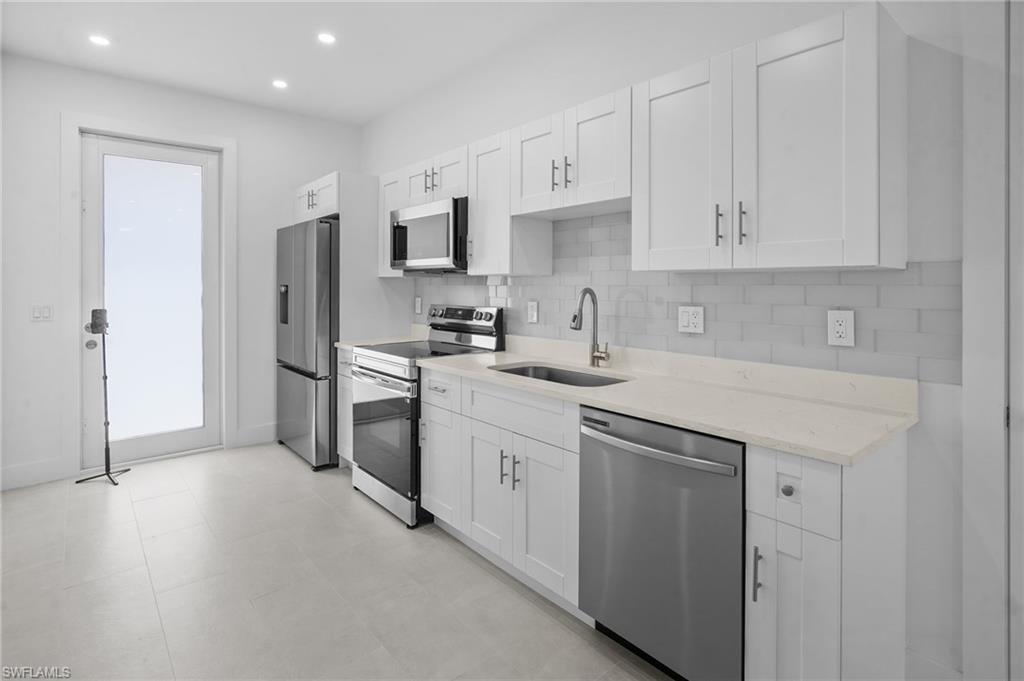 2936 40th Avenue Southeast Naples, FL 34117 - Photo 7 of 49 Kitchen featuring decorative backsplash, appliances with stainless steel finishes, light stone counters, white cabinets, and recessed lighting