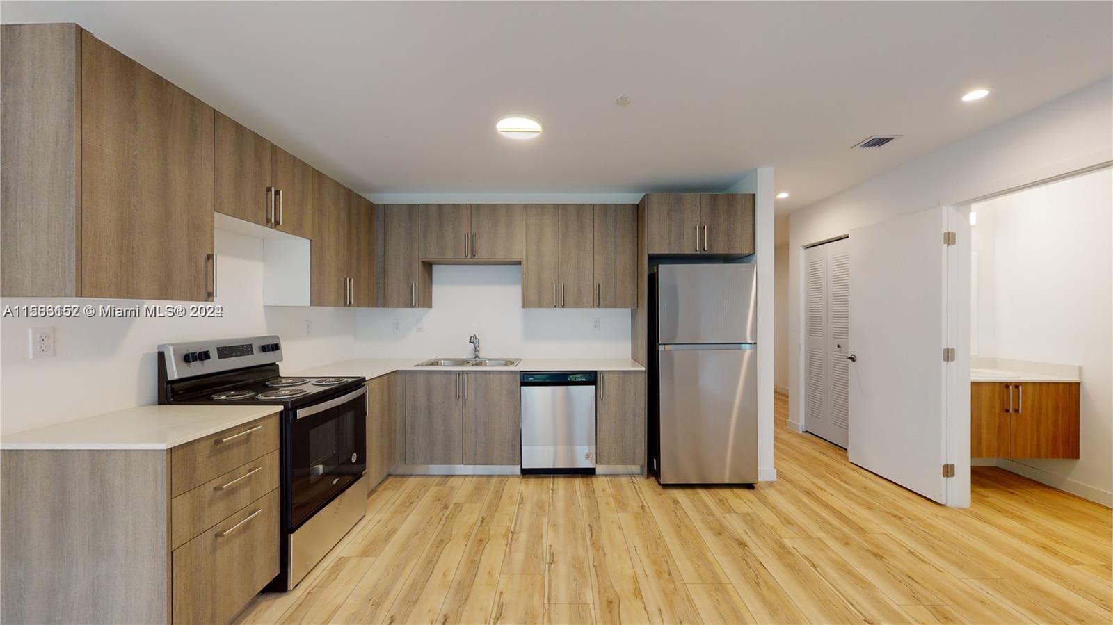 24705 Southwest 129th Avenue, Unit 109 Homestead, FL 33032 - Photo 1 of 22 a kitchen with stainless steel appliances granite countertop a stove a refrigerator a sink a microwave oven with white cabinets and wooden floor