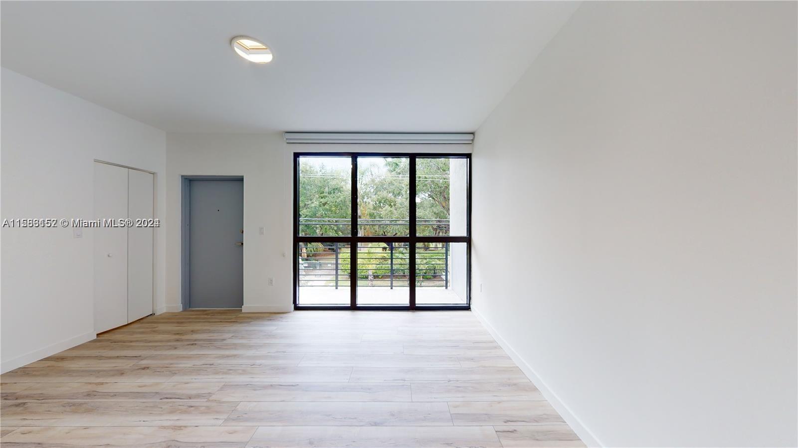 24705 Southwest 129th Avenue, Unit 109 Homestead, FL 33032 - Photo 14 of 22 a view of an empty room with wooden floor and a window