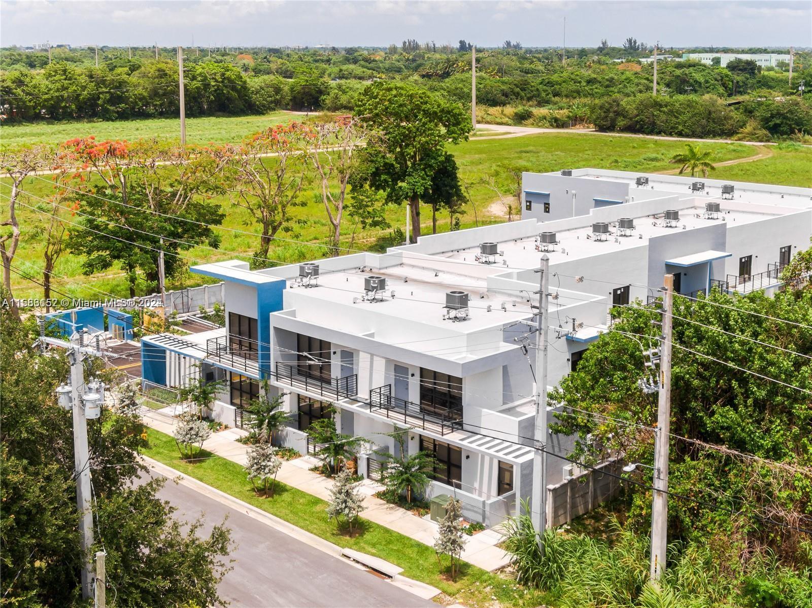 24705 Southwest 129th Avenue, Unit 109 Homestead, FL 33032 - Photo 20 of 22 a view of a white house with a big yard and large trees