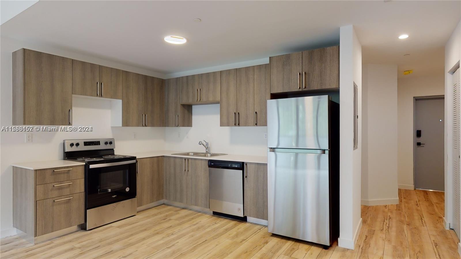 24705 Southwest 129th Avenue, Unit 109 Homestead, FL 33032 - Photo 3 of 22 a kitchen with stainless steel appliances a refrigerator and a stove top oven