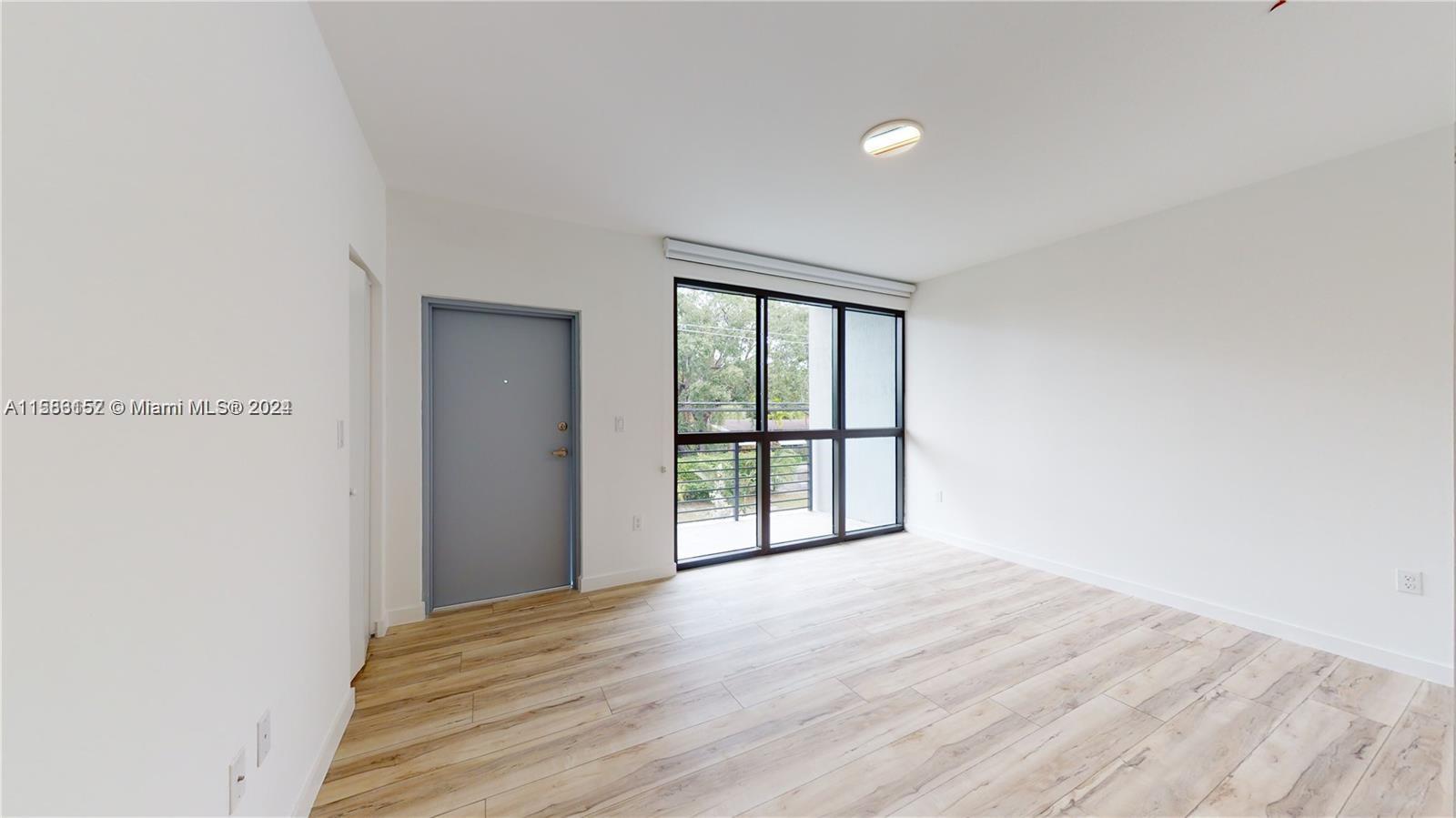 24705 Southwest 129th Avenue, Unit 109 Homestead, FL 33032 - Photo 5 of 22 a view of an empty room with wooden floor and a window