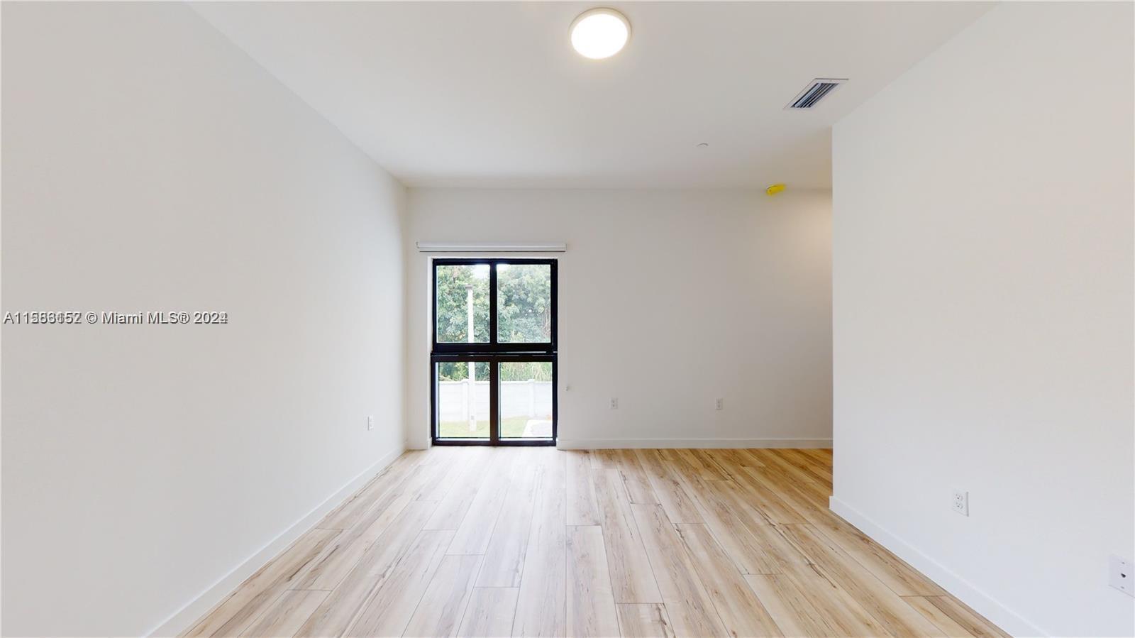 24705 Southwest 129th Avenue, Unit 109 Homestead, FL 33032 - Photo 8 of 22 a view of an empty room with wooden floor and a window