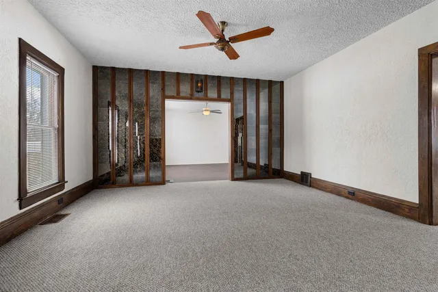 an empty room with closet and a ceiling fan