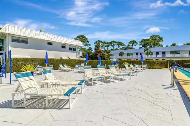 a view of a swimming pool with lawn chairs under an umbrella